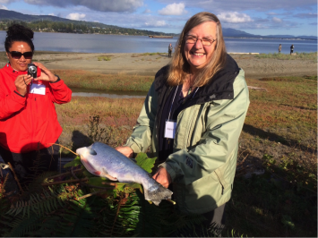  The distinguished ethnobotanist Professor Nancy Turner holds a platter she made with local plants on which the salmon was steamed in the pit-fire (photo – Iain MacKinnon)